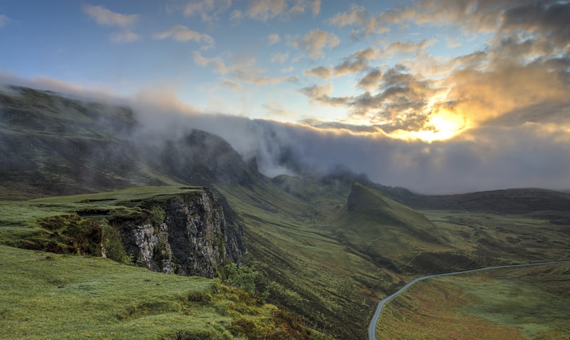 Soft morning mist settling over a rolling green landscape at sunrise